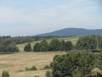 Na fotografii z vletu jsou pole, louky, lesy a kopec.