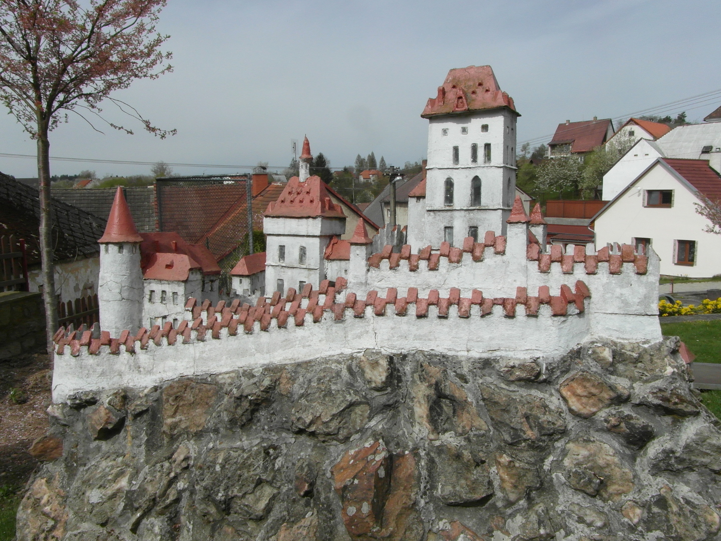 Miniatura Karltejna se nachz na svahu na skalce tho pdorysu, kter piblin odpovd pdorysu skutenho hradu. Stny hradu jsou
  bl a stechy erven. Pod miniaturou je minigolfov hit. Karltejn  je od severovchodu. Sv. K, Nanebevzet Panny Marie a Csask palc.