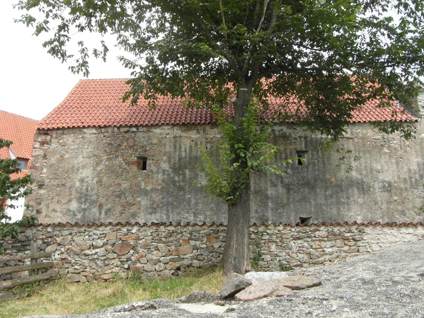 Od jihozpadu je vidt bon stna pcharu. Jsou pkn vidt ti stlnov vtrac
  oknka. Vlevo za pcharem vykukuje kousek obytn budovy, z n je vidt pedevm
  nehistorick sten okno. Na bon stn je sten opadan star omtka. Ped 
  pcharem je ze bez omtky. Stechy jsou prejzov. Uprosted ped zdi pcharu je 
  mohutn strom. Koruna stromu zan a v polovin vky stechy pcharu a vrek 
  koruny pchar znan pevyuje.