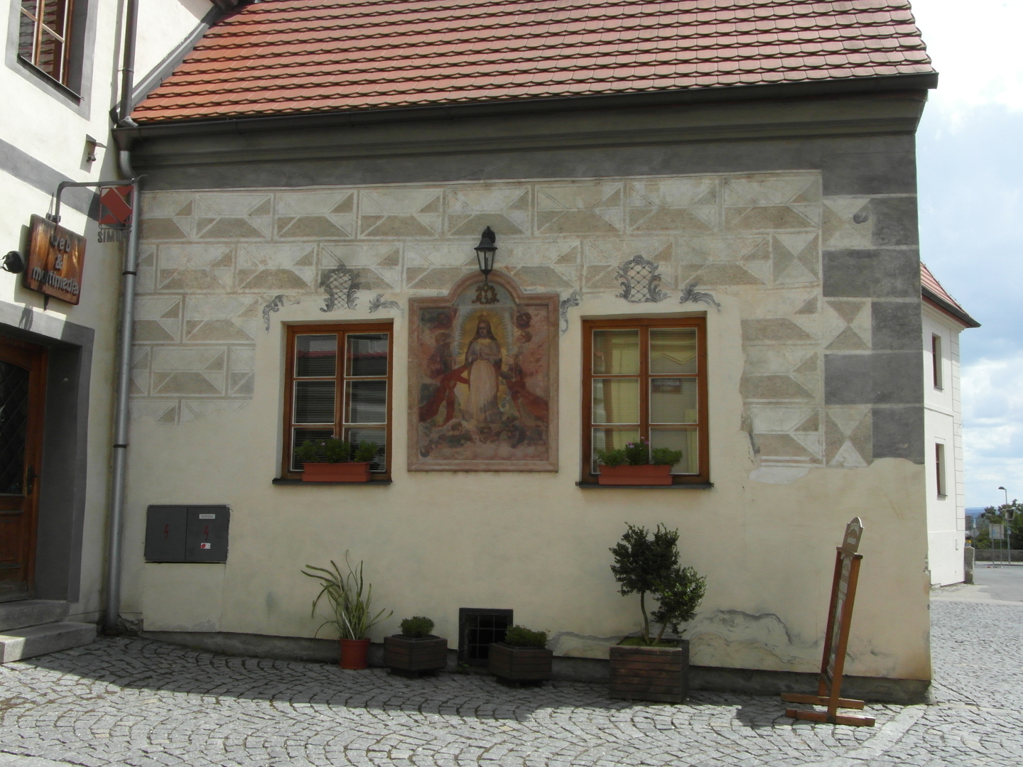 Na fotografii je bok domu v Klokotsk ulici. Mezi jeho okny je ve tukovm rmeku o nco vtm ne jedno okno zarmovan freska.
          Stna domu je od doln sti domu opatena tm zachovanou sgrafitovou vzdobou.