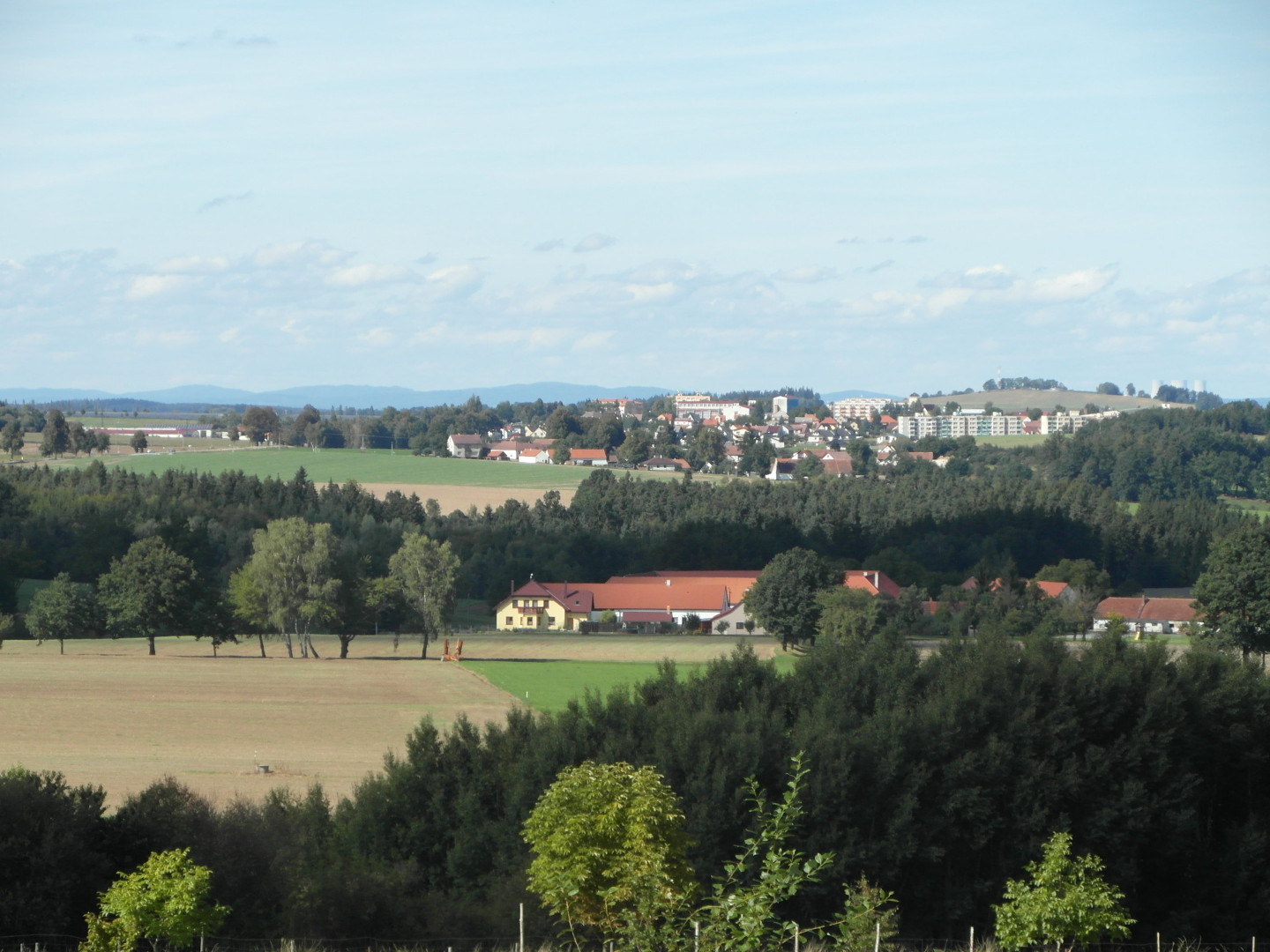 Na fotografii jsou vidt stromy, 
  lesy, louky, pole, domy, hospodsk staven, msto a na obzoru hory. Ble je dvr Heben.
  Vlevo je velk upraven lut patrov stavba s balkonem, pak dal budovy a nakonec pln vpravo je
  ni bl trochu zchtral hospodsk budova. Z Velena jsou vidt pedevm domky a sdlit.
  Napravo na obzoru jsou vidt chladic ve Jadern elektrrny Temeln.